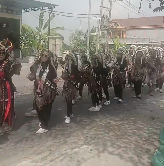 Peserta karnaval saat melintasi salah satu ruas jalan di Desa Dibee.